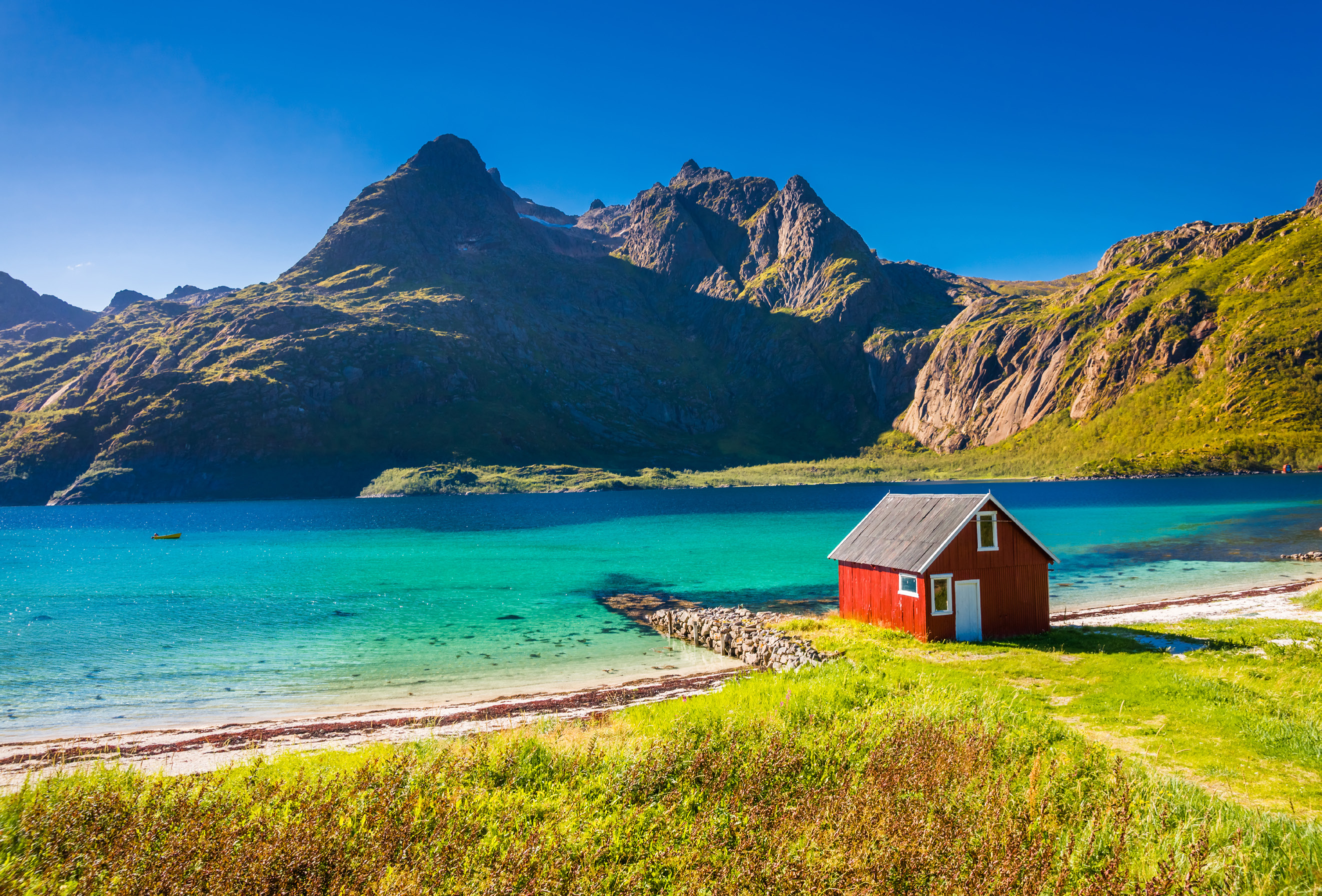 Türkisfarbener Fjord mit Bergen und rotem Bootshaus in Norwegen